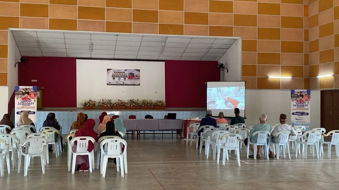 Peserta kursus menghadap pentas Dewan Tan Sri Yusof Nor sambil menonton tayangan taklimat, diapit banner pakej Moh Poie Mokah