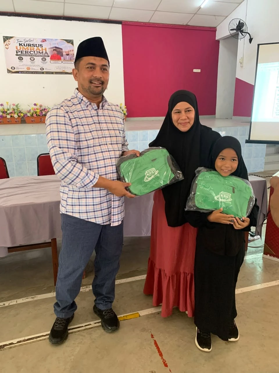 YB Dato’ Mohd Zaidy menyerahkan beg KRS kepada seorang jemaah wanita bersama anaknya
