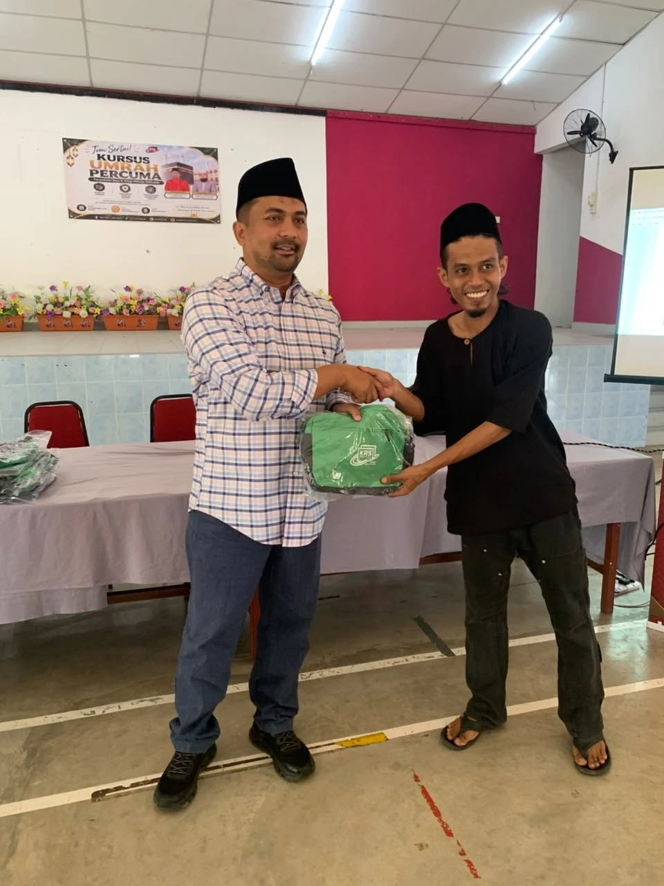 YB Dato’ Mohd Zaidy menyerahkan beg KRS sambil berjabat tangan dengan seorang jemaah lelaki