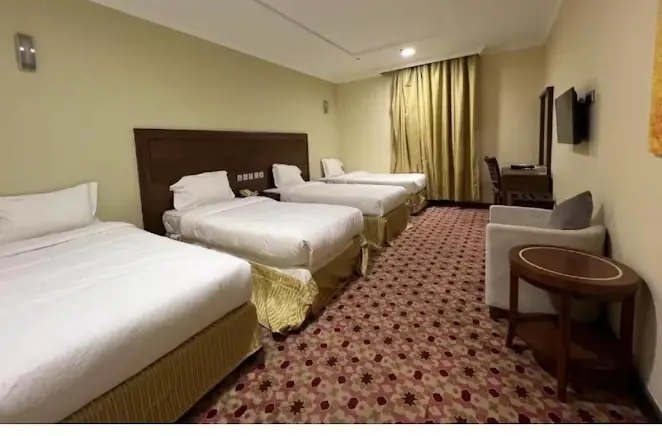 Bilik berkumpulan di Dar al-Salah Hotel Aziziyah dengan empat katil, meja tulis, televisyen dan ruang duduk