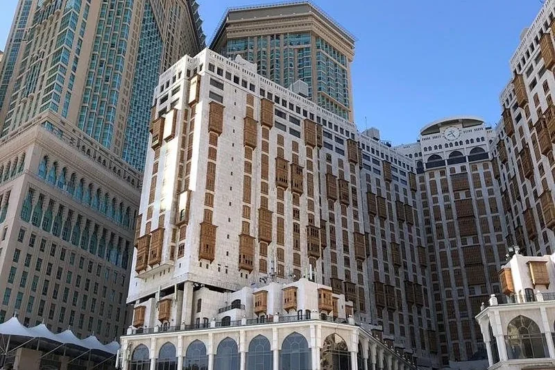 Bangunan Makkah Hotel & Towers di Makkah pada waktu siang, tingkap mashrabiya kayu di sepanjang fasad dan Menara Jam Makkah kelihatan di sebelah kiri