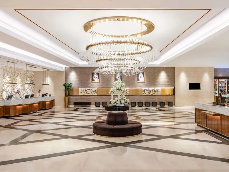 Ruang lobi M&ouml;venpick Hajar Tower dengan candelier besar, kaunter penerimaan tetamu dan lantai marmar bercorak